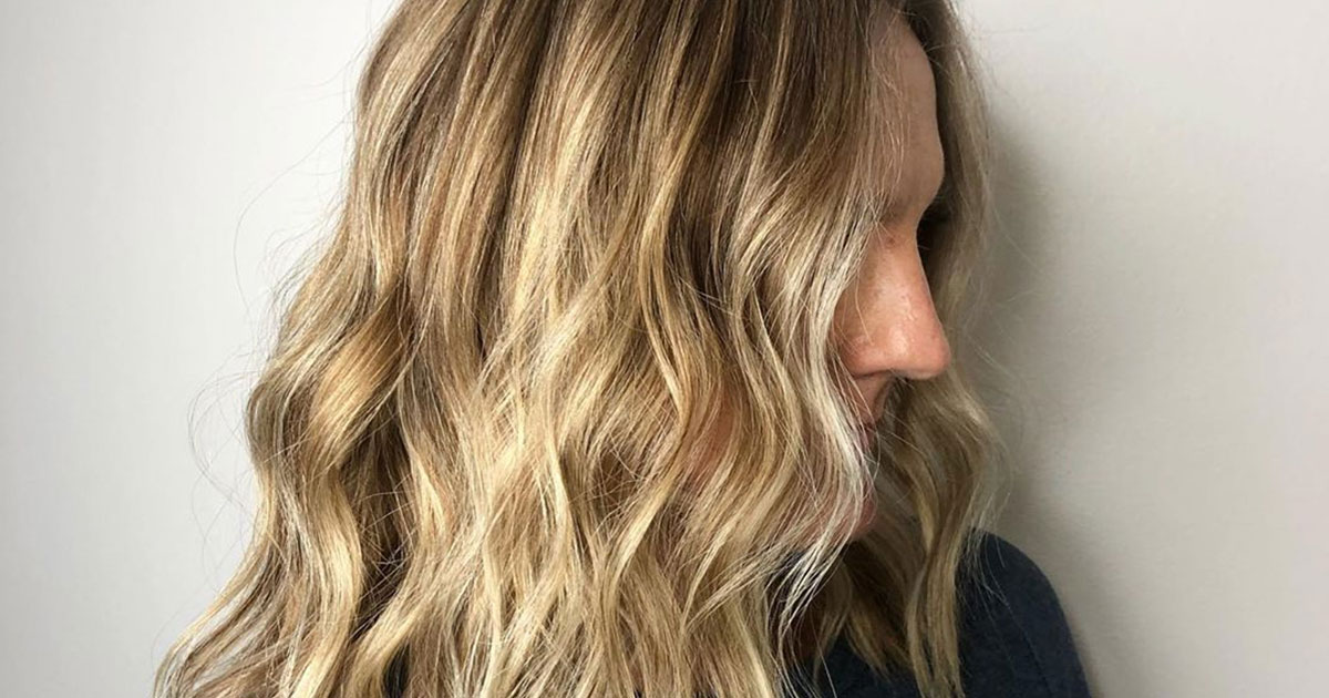 Profile view of a person with long, wavy blonde highlighted hair, focusing on the hairstyle and color. - K. Charles & Co. in Schertz, TX