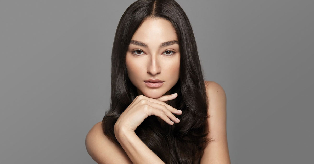 Portrait of a woman with a waxing hairstyle, resting her chin on her hand, against a gray background. - K. Charles & Co. in Schertz, TX