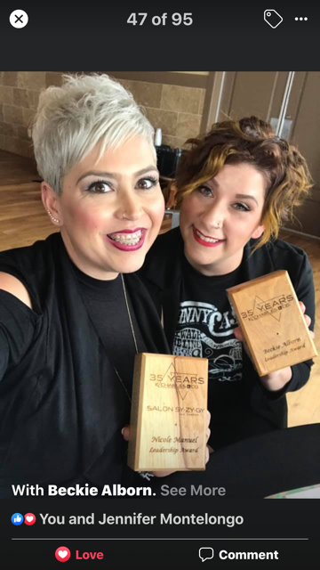 Two smiling women holding wooden plaques, one with short grey hair and the other with brown hair, inside a building. - K. Charles & Co. in Schertz, TX
