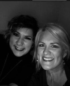 Two women smiling at the camera in a black and white photo. one has short hair and earrings, the other sports a nose ring. - K. Charles & Co. in Schertz, TX