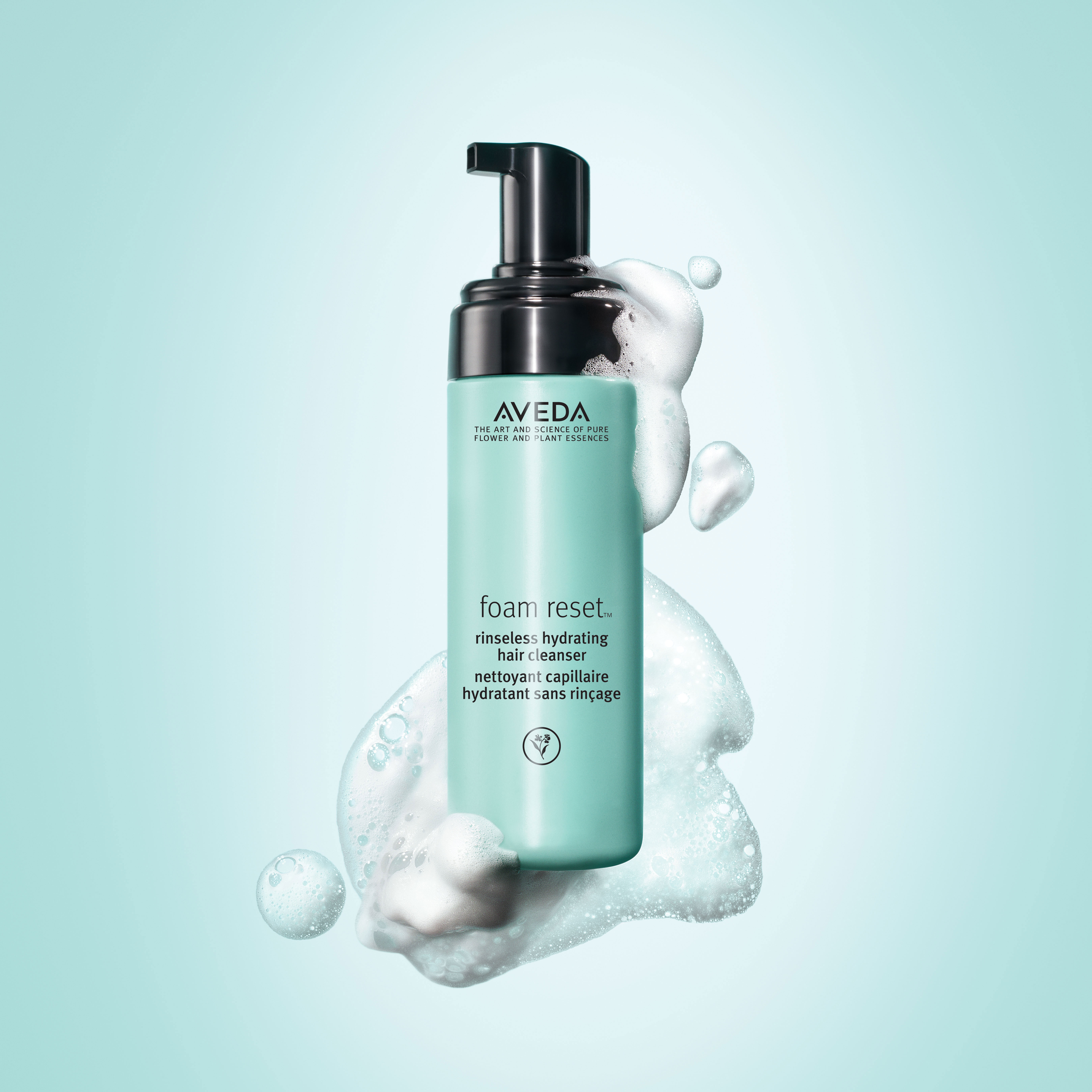 A bottle of aveda foam reset hair cleanser surrounded by bubbles on a teal background. - K. Charles & Co. in Schertz, TX