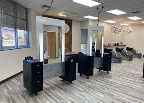 Interior of a modern hair salon showing styling stations with mirrors, chairs, and a waxing area with basins in the background. - K. Charles & Co. in Schertz, TX