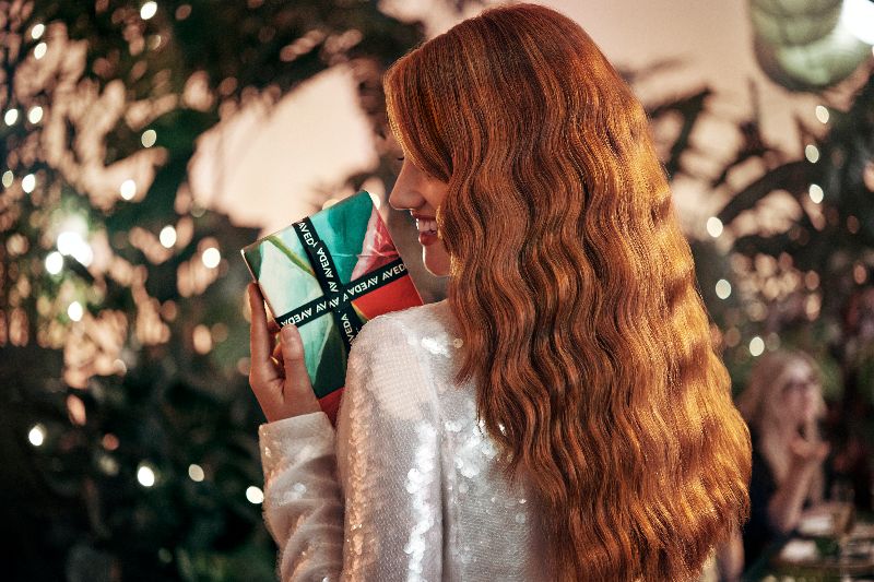 Woman with long red hair reading a book at a festive party, surrounded by greenery and soft lighting. - K. Charles & Co. in Schertz, TX