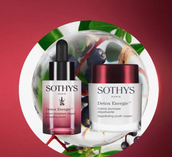 Two sothys skincare products, a serum and a cream, are displayed against a backdrop of mixed berries and hair color-inspired gradient from green to purplish hues. - K. Charles & Co. in Schertz, TX