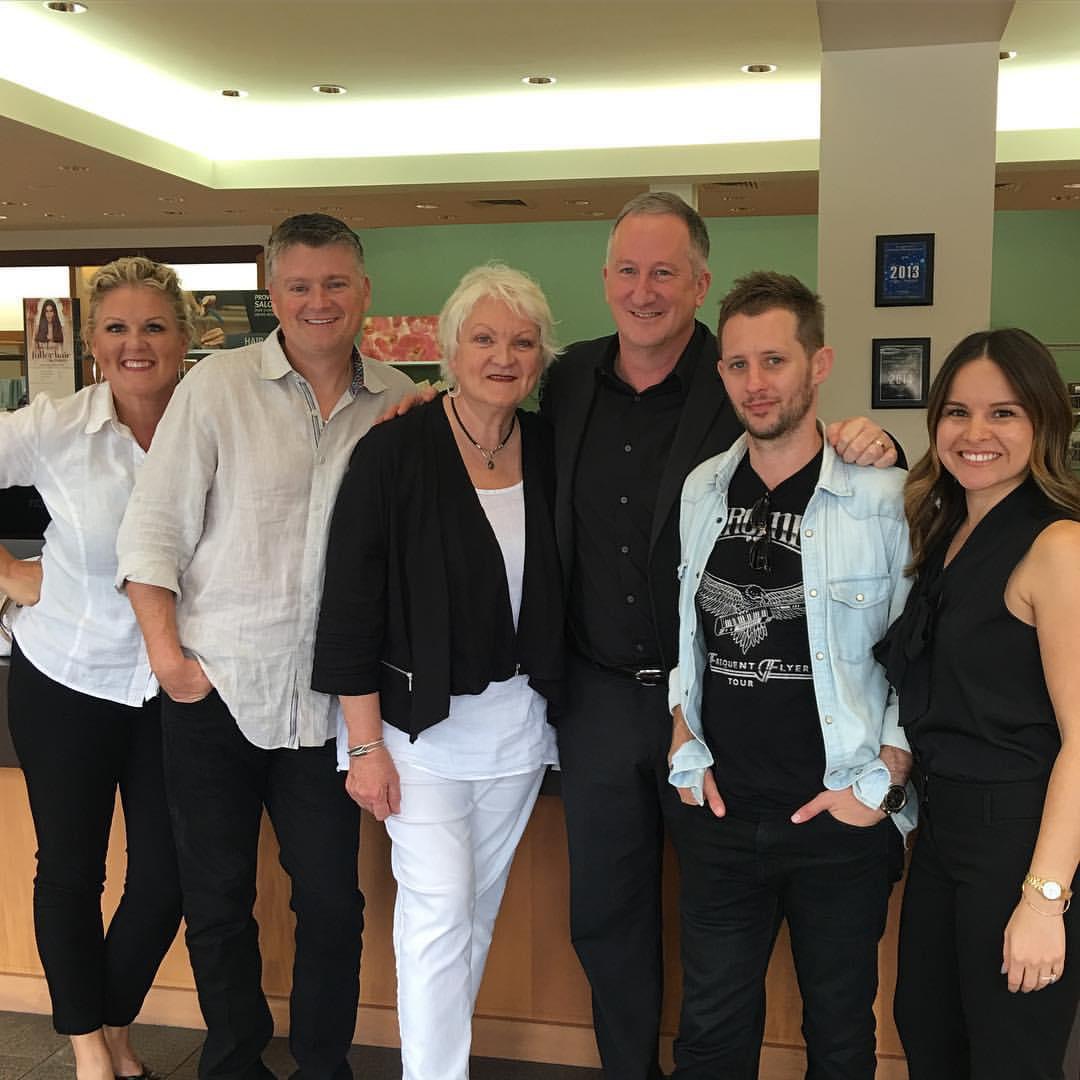 Group of six adults posing together in a lobby, smiling at the camera, with a poster board in the background. - K. Charles & Co. in Schertz, TX