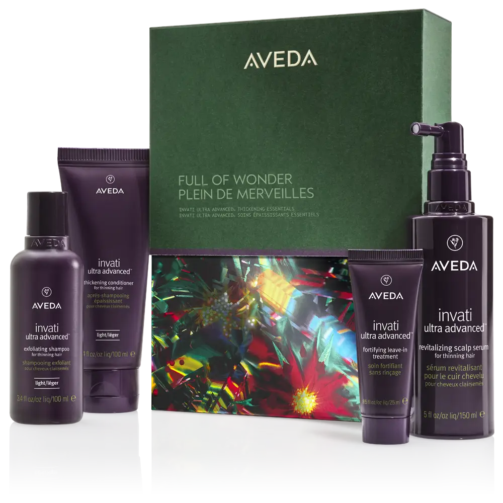 A gift box labeled “Aveda Full of Wonder” is displayed with four Aveda Invati Ultra Advanced hair care products in purple packaging arranged in front of it. - K. Charles & Co. in Schertz, TX