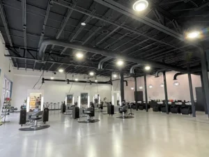 Spacious modern hair salon with several styling stations, black chairs, large mirrors, and bright overhead lighting in an open, industrial-style interior. - K. Charles & Co. in Schertz, TX