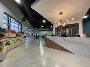 Modern salon interior featuring a large reception desk, contemporary lighting, product displays on the left, and styling stations visible in the background. - K. Charles & Co. in Schertz, TX