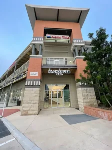 A two-story commercial building with signs for "K Charles & Co." on the ground floor and "Asian Plate" on the upper level, viewed from the sidewalk entrance. - K. Charles & Co. in Schertz, TX